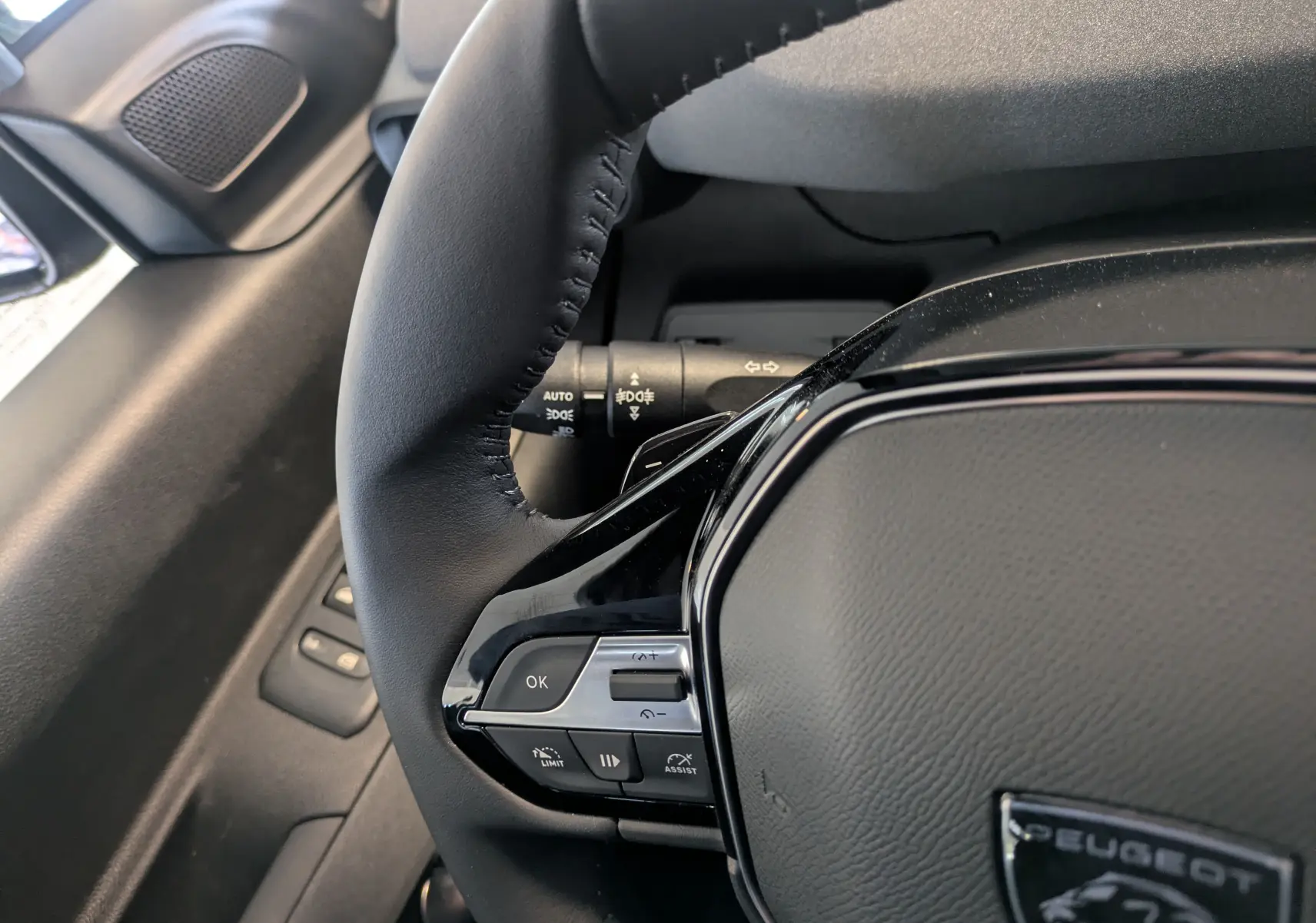 Gros plan sur le volant noir du Peugeot Rifter 2025, montrant les commandes multifonctions côté gauche.