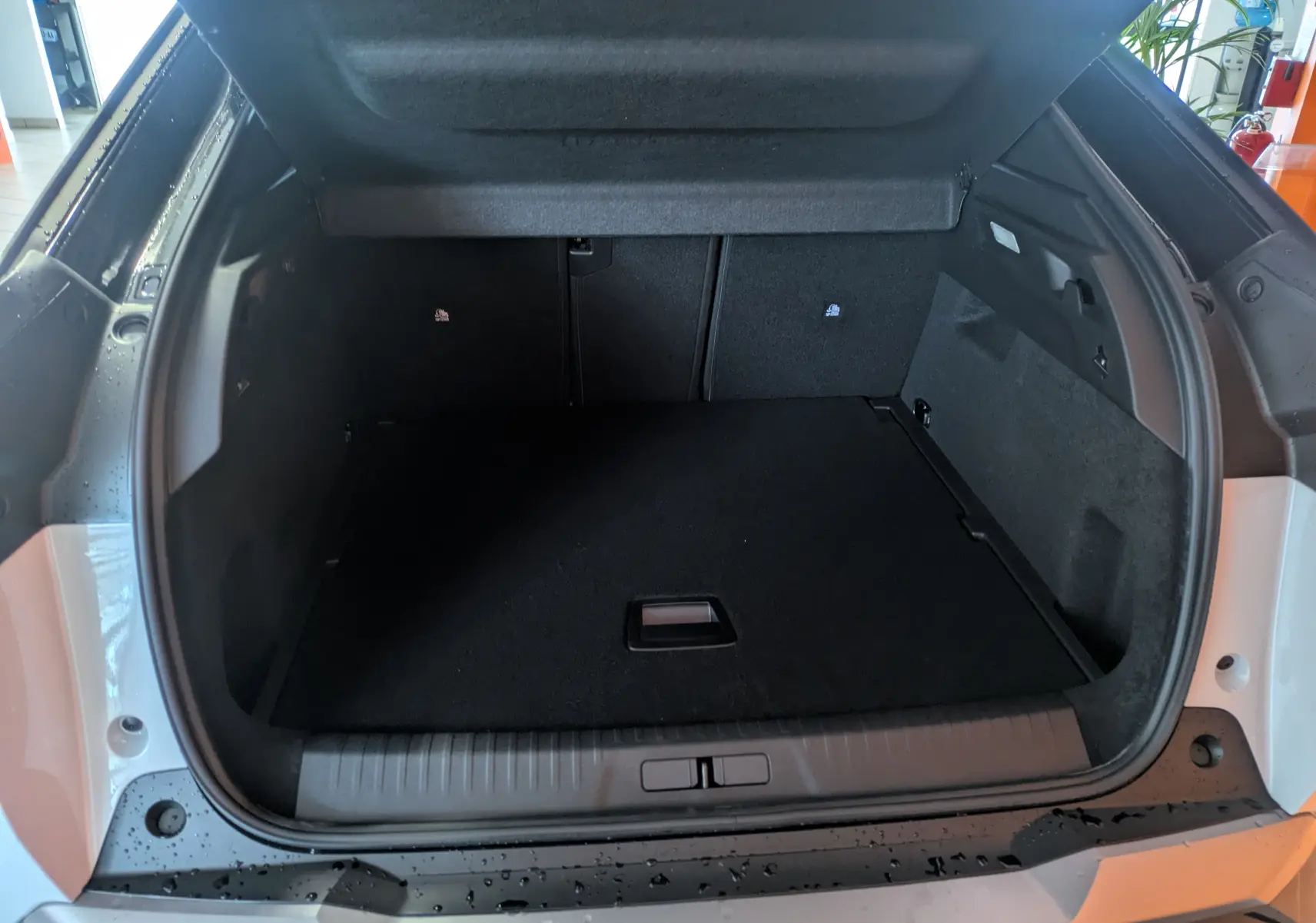 Coffre ouvert vu de l'arrière d'un Peugeot 3008 blanc Okenite, montrant un espace de chargement propre et spacieux.