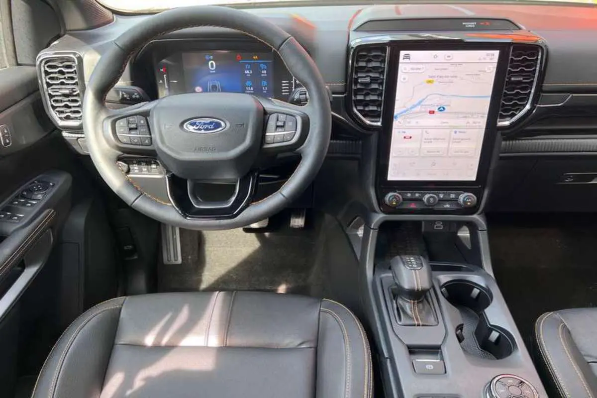 Vue intérieure du tableau de bord et volant cuir du Ford Ranger Wildtrak Plus avec écran tactile vertical et sellerie noire.