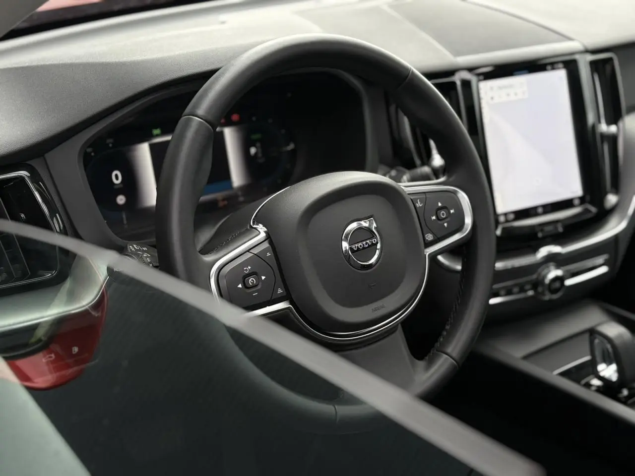 Vue rapprochée du volant noir et du combiné d'instruments digital du Volvo XC60 T6 AWD PHEV 2024.