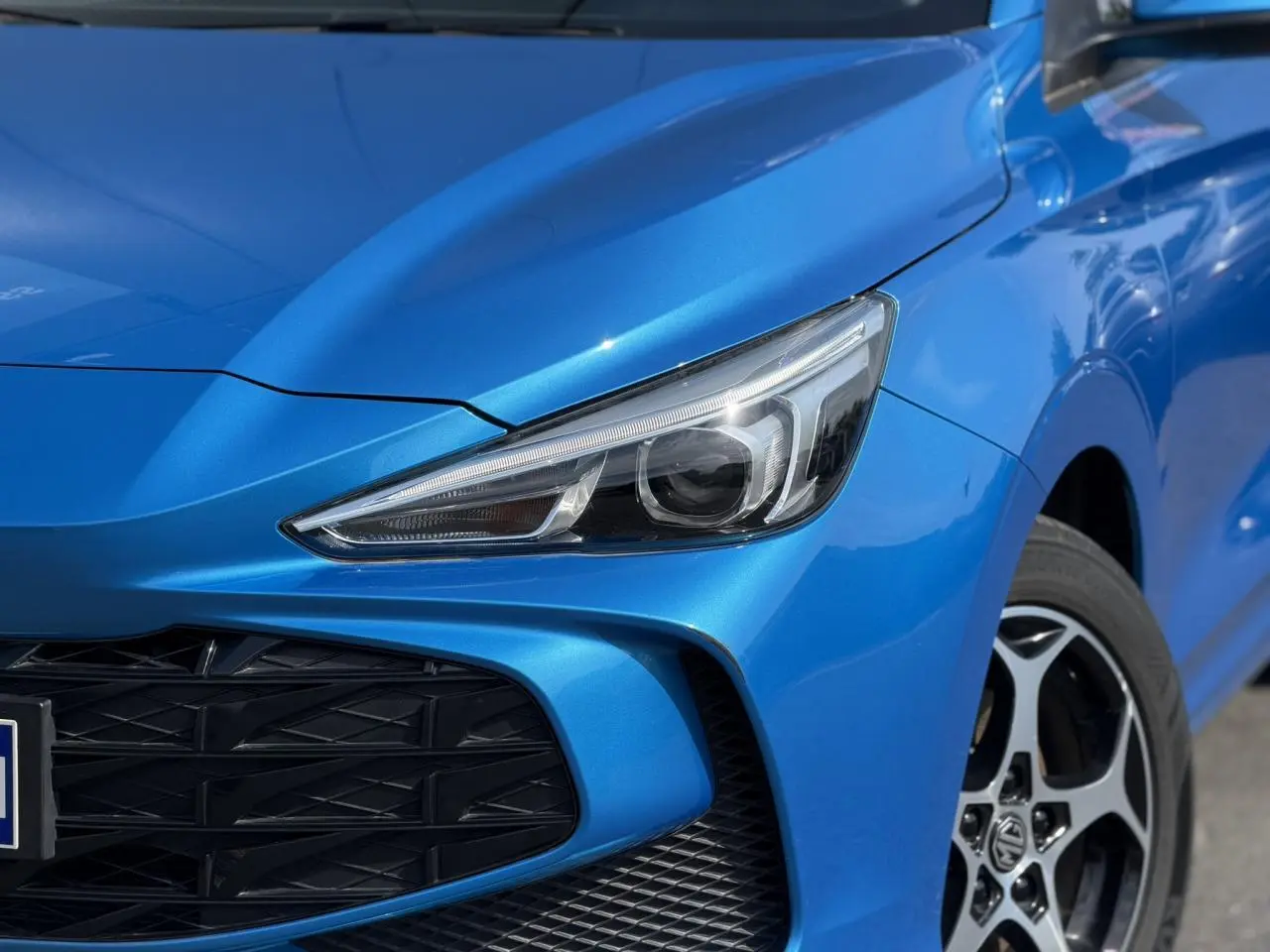 Gros plan sur l'avant droit bleu Como du MG3 1.5 Hybrid+ 195 Comfort, mettant en valeur le phare LED et la calandre noire.