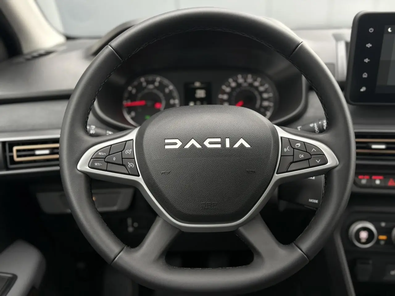 Gros plan sur le volant noir DACIA avec commandes intégrées, tableau de bord et écran tactile du Sandero Stepway 2025.
