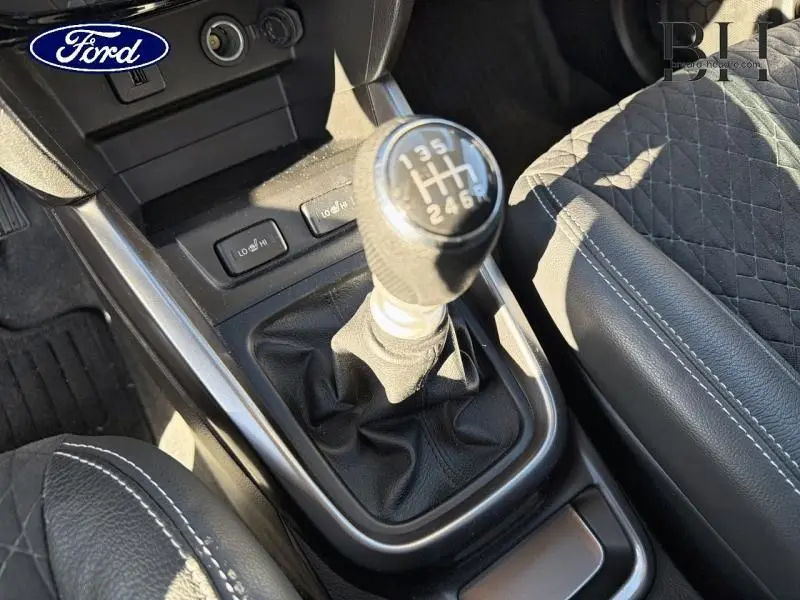 Le levier de vitesse manuel en gros plan avec sellerie cuir noire et coutures blanches dans un Suzuki Vitara Galactic Gray.