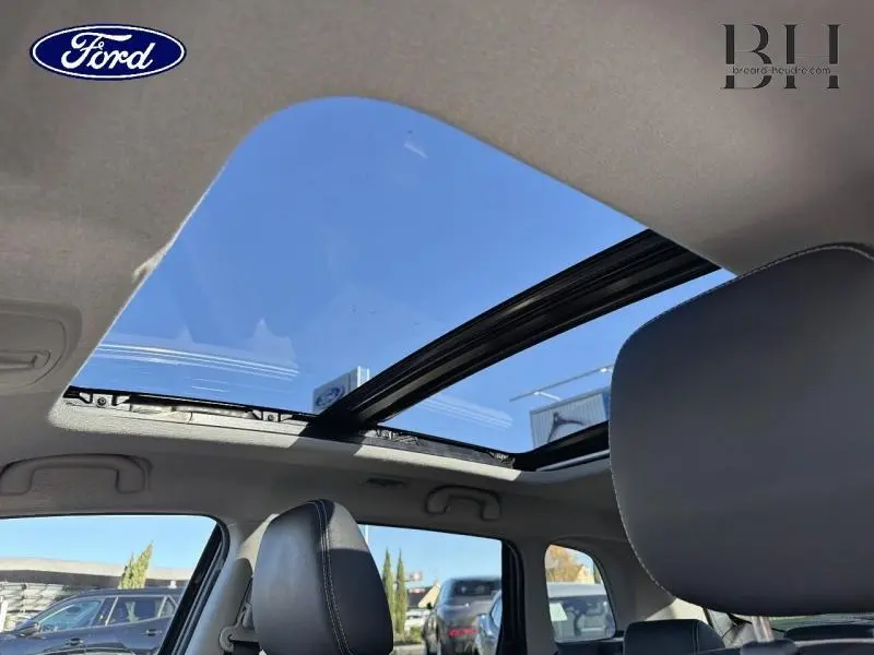 Toit panoramique en verre ouvert vu de l'intérieur d'un Suzuki Vitara Galactic Gray, sièges en cuir noir visibles