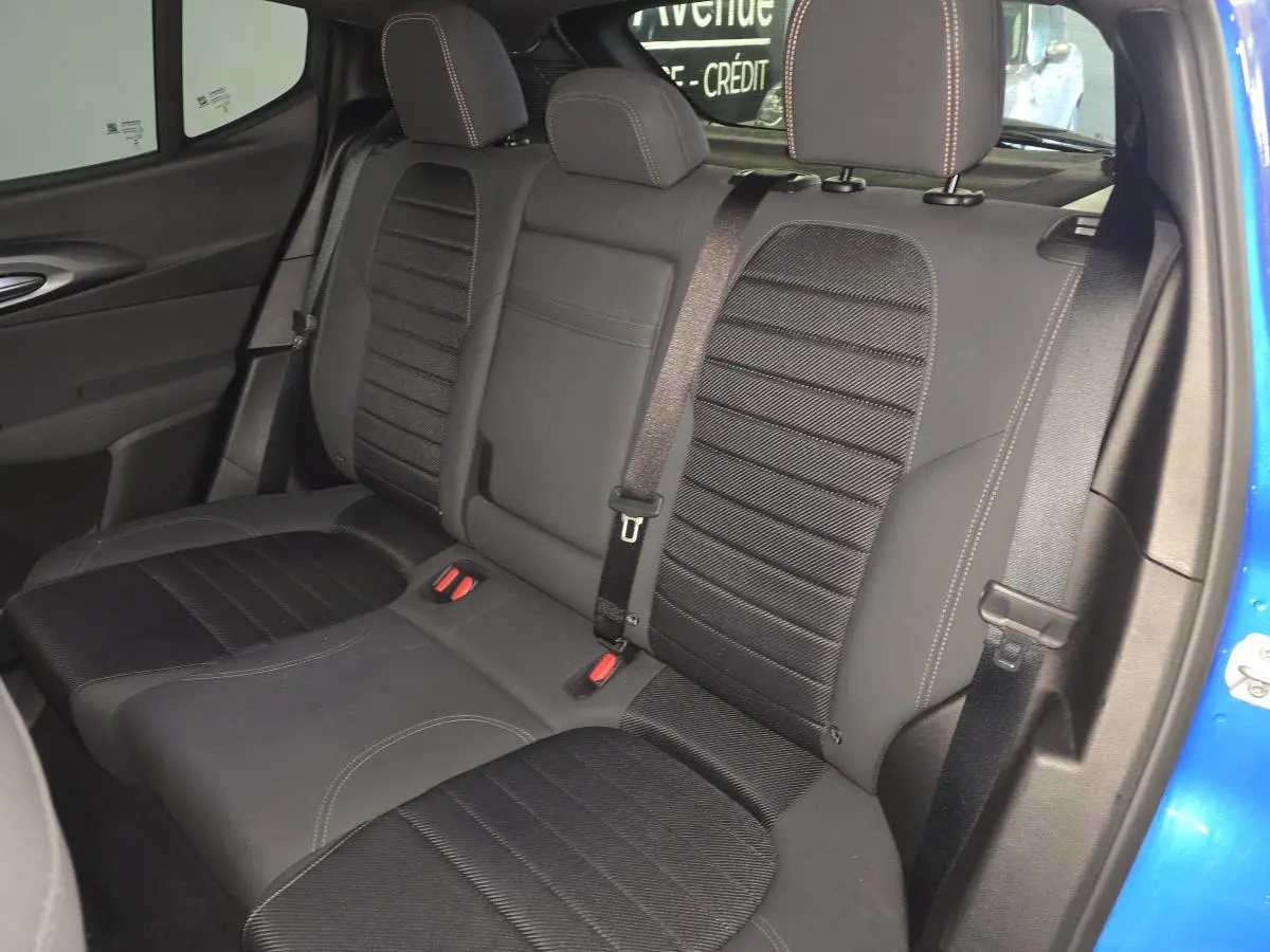 Vue intérieure de la banquette arrière noire avec surpiqûres beige de l'Alfa Romeo Tonale bleu, côté droit ouvert.
