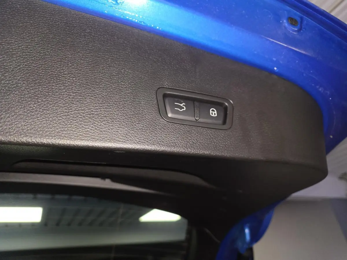 Bouton d'ouverture et de verrouillage du hayon sur la partie intérieure du coffre bleu d'une Alfa Romeo Tonale 2024.