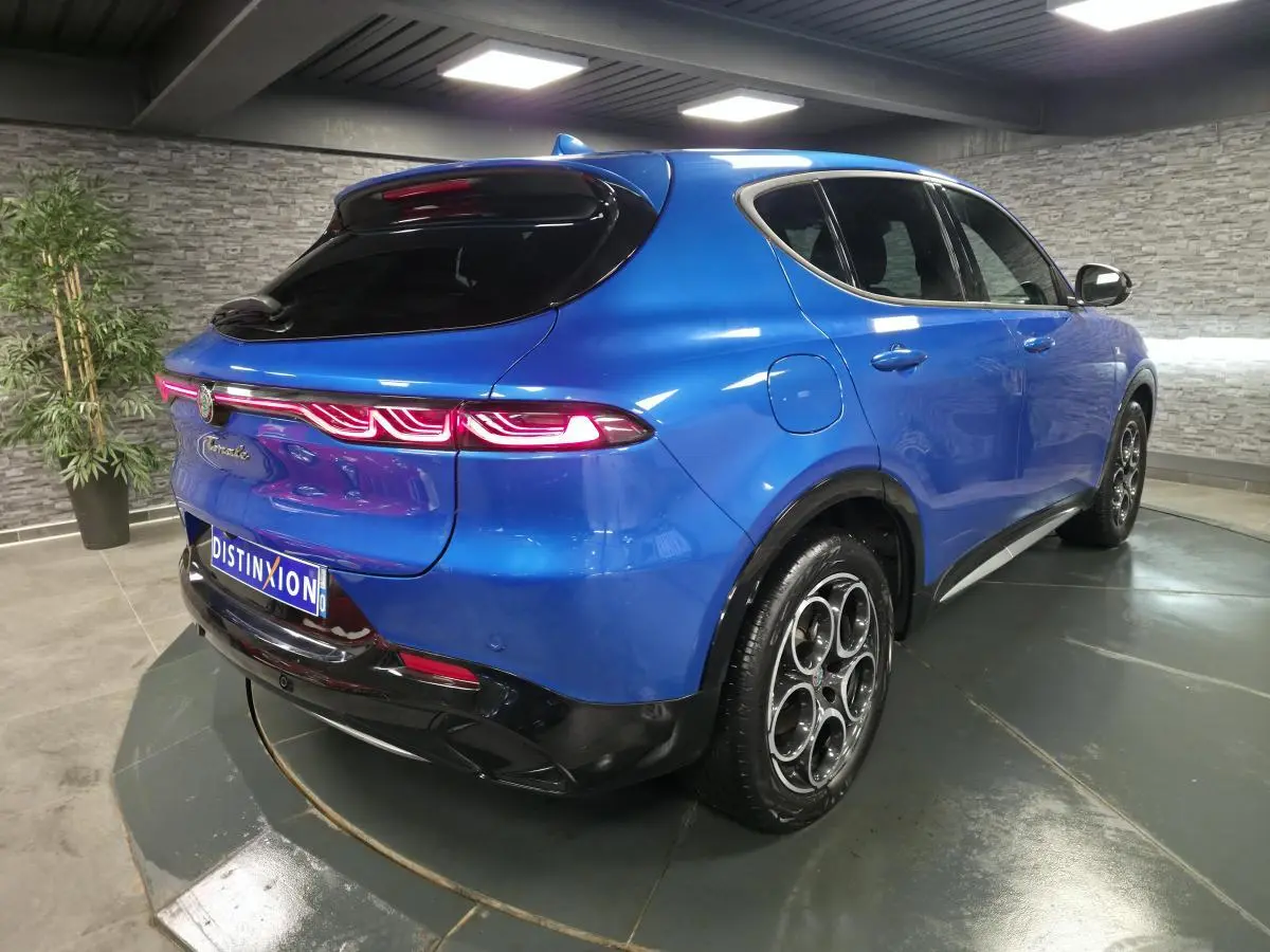 Vue 3/4 arrière droite de l'Alfa Romeo Tonale 1.3 PHEV bleu métallisé avec feux arrière LED et jantes alliage 18 pouces.