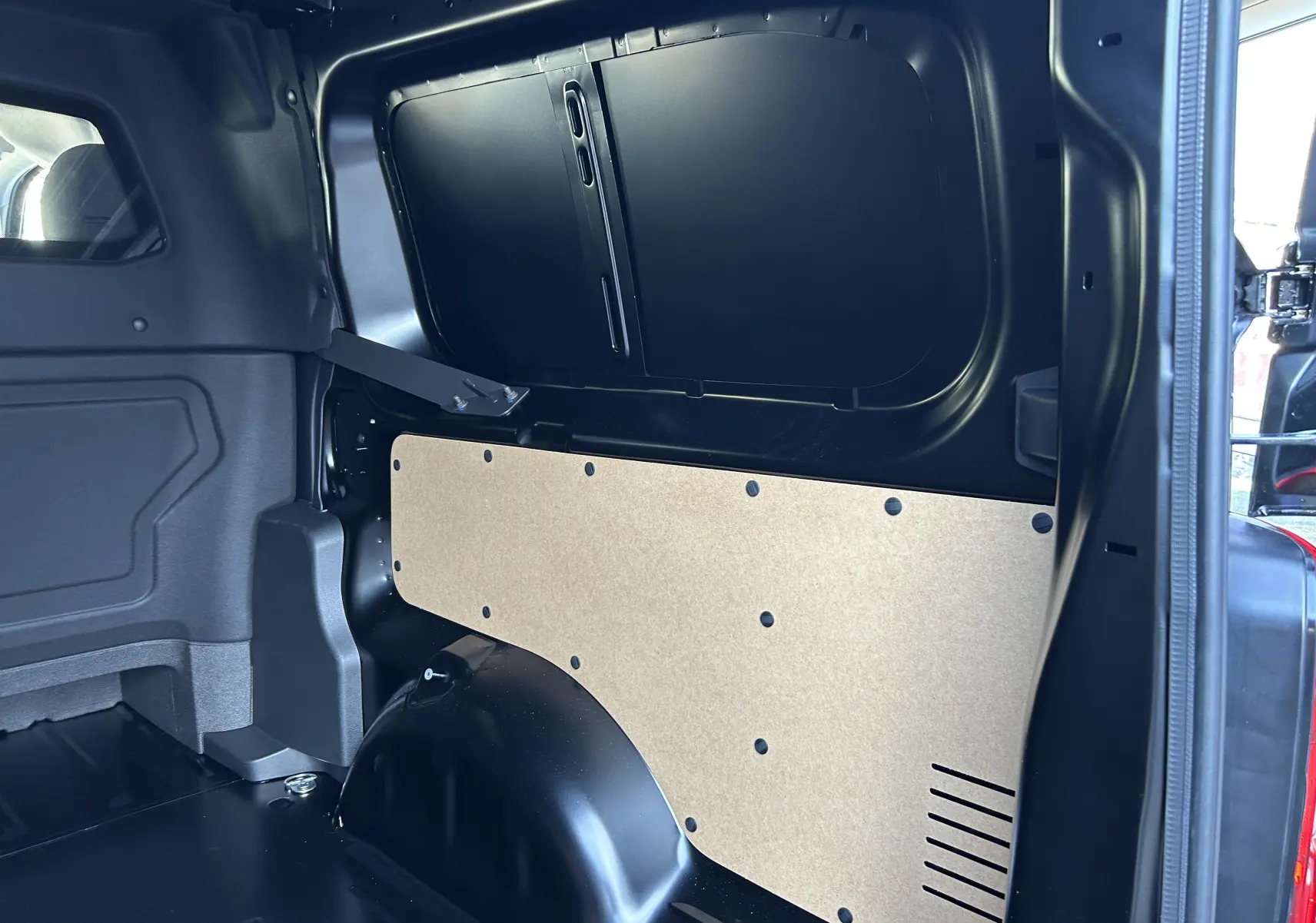 Vue intérieure côté droit de l’espace de chargement noir du Citroën Jumpy Cabine Approfondie 2025 avec panneau de protection beige.