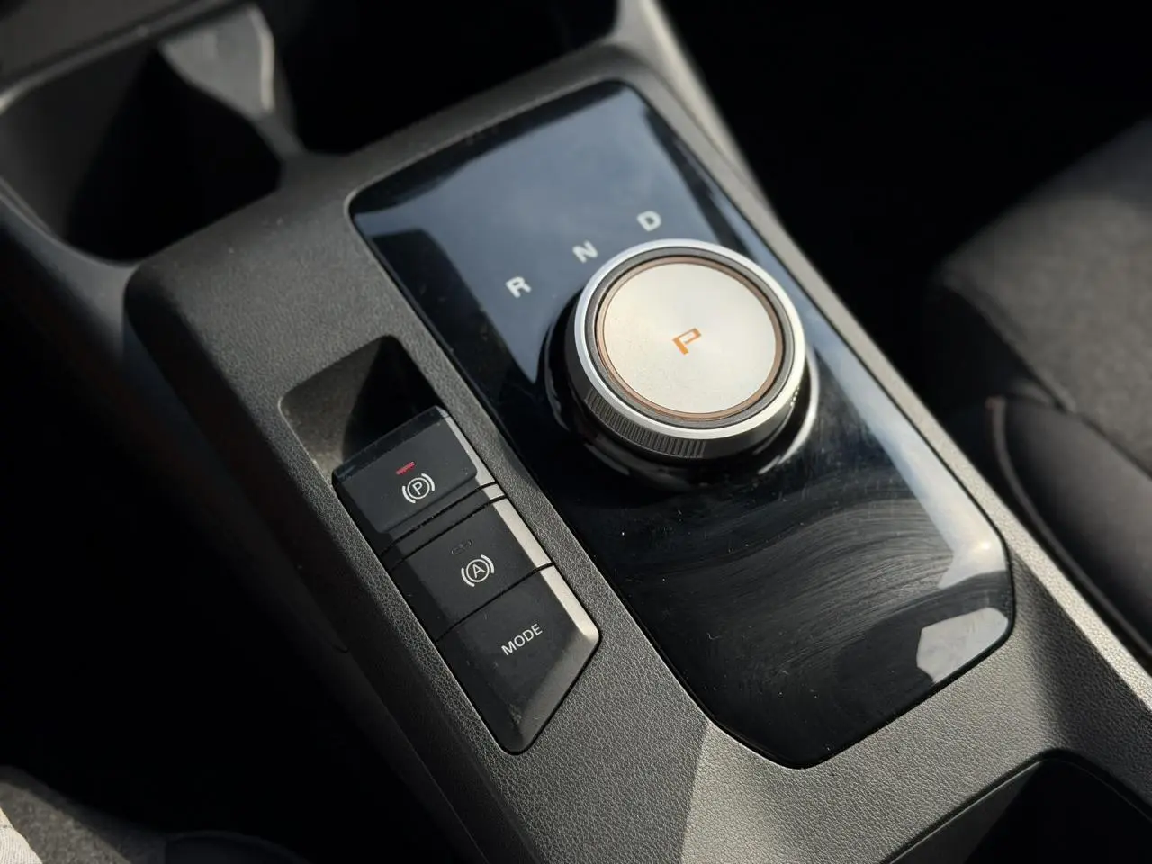Gros plan sur la commande rotative de boîte automatique et frein électronique dans l’habitacle noir du MG3 2024.