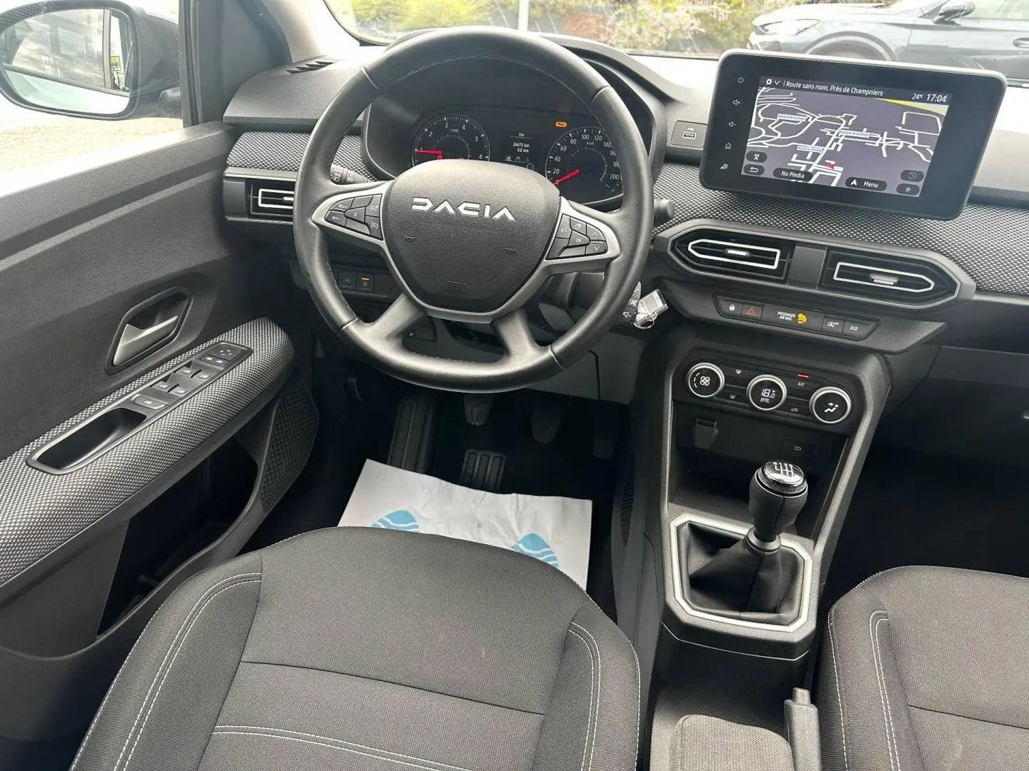 Vue intérieure centrée sur le poste de conduite du Dacia Jogger, volant multifonction et écran tactile visible.