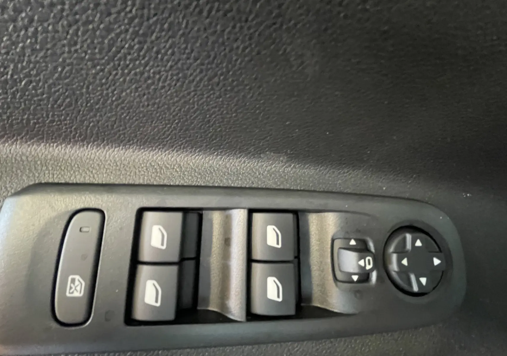 Panneau de commandes des vitres électriques et rétroviseurs sur la portière noire d'un Citroën Berlingo 2025.