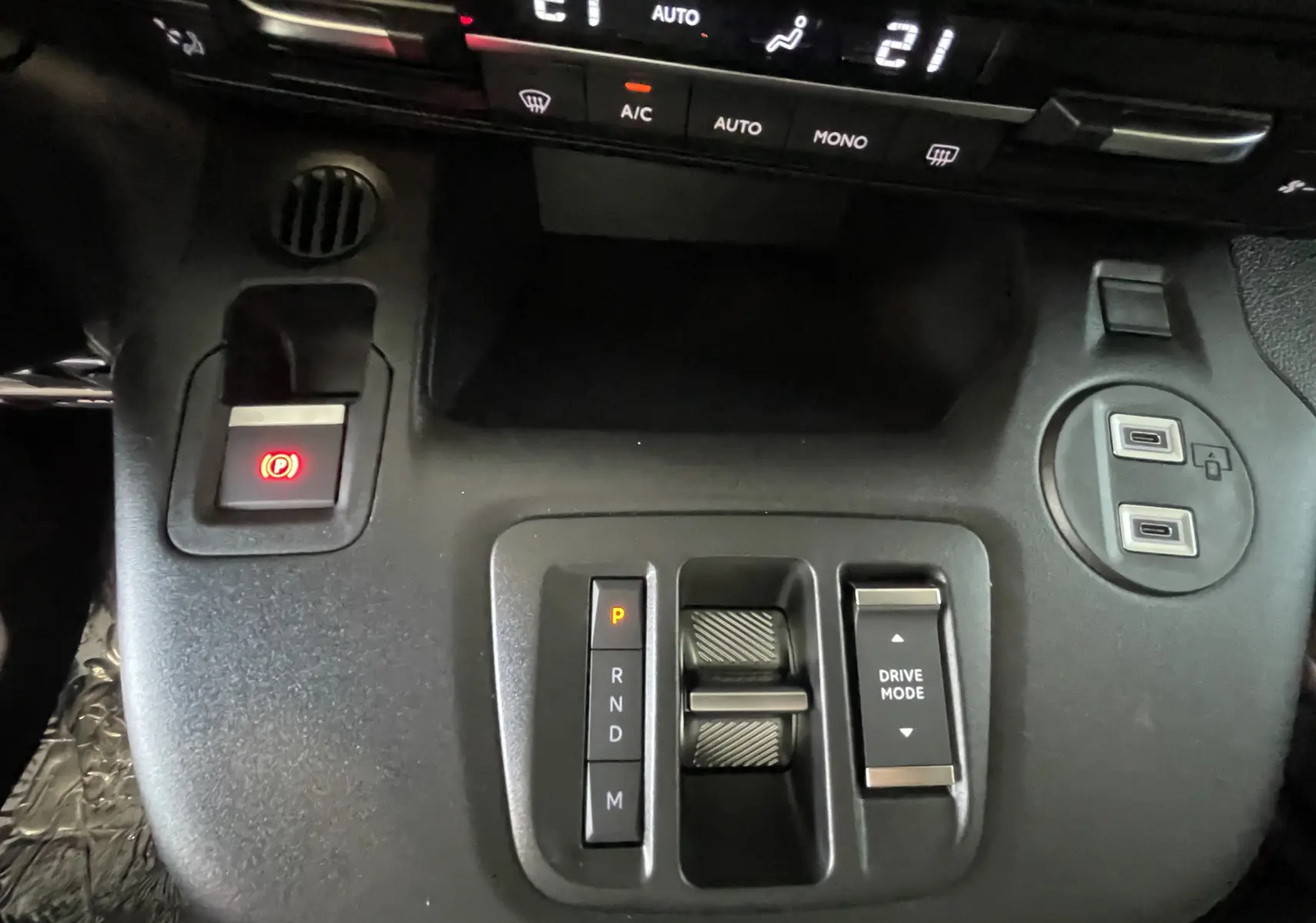 Vue rapprochée de la console centrale noire du Citroën Berlingo 2025, avec commandes de boîte auto et climatisation digitale.