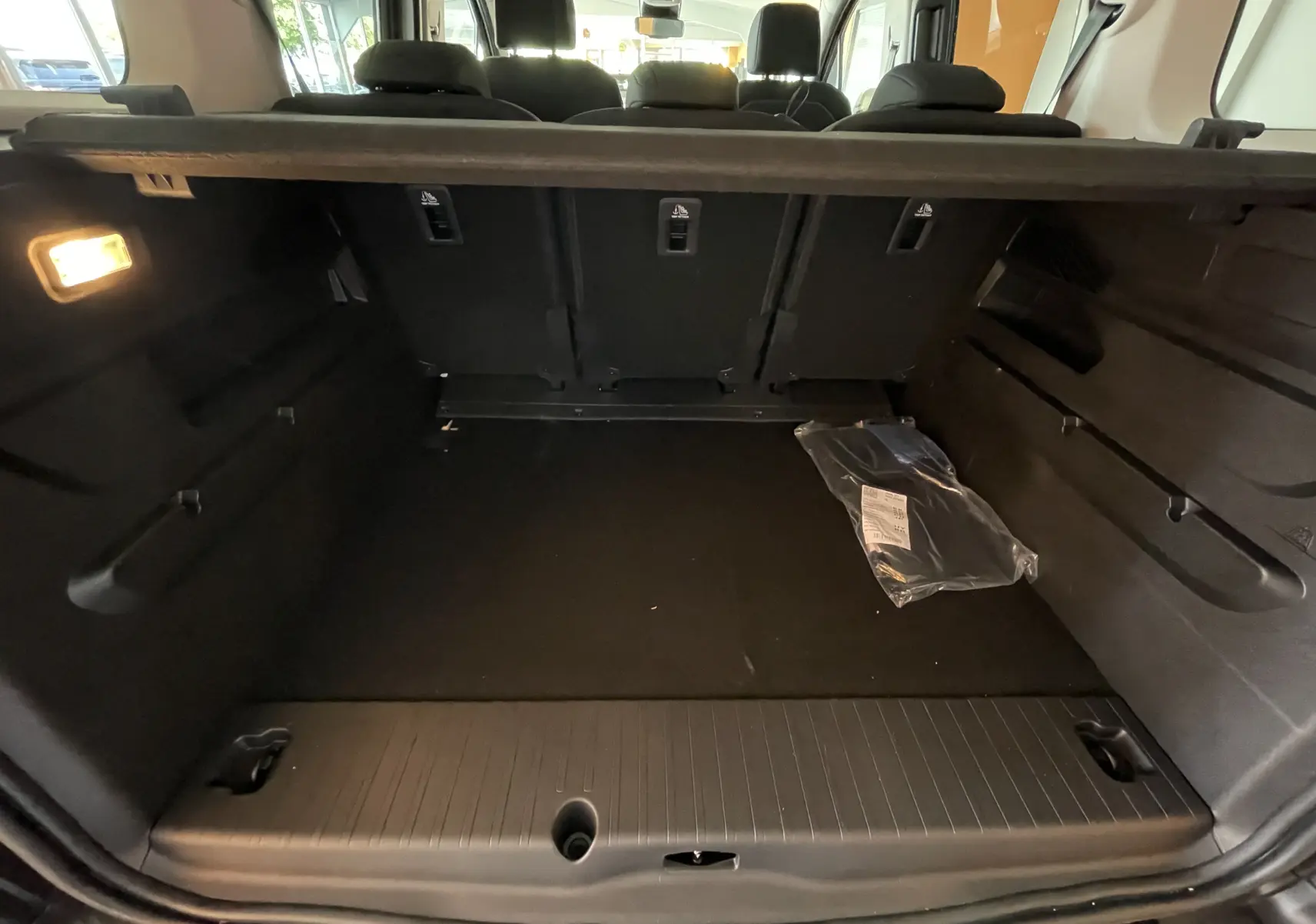 Coffre noir du Citroën Berlingo 2025 vu de l'arrière, avec banquette arrière rabattue et éclairage intérieur allumé.