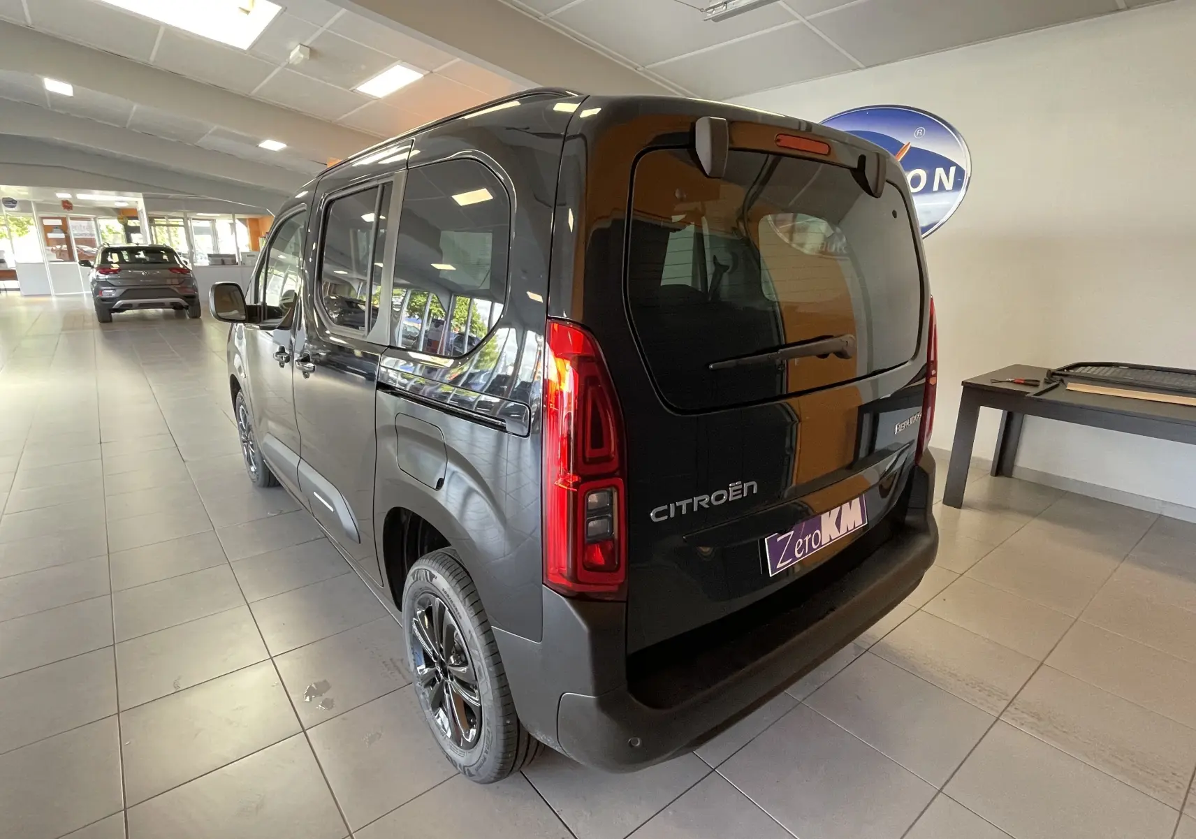 Vue 3/4 arrière droite du Citroën Berlingo noir 2025 avec feux arrière LED et logo visible en showroom.