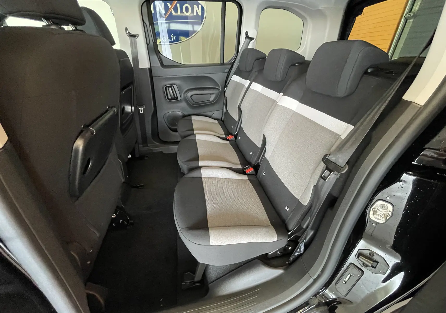 Vue intérieure côté droit des sièges arrière gris et noirs du Citroën Berlingo 2025 noir avec porte ouverte.