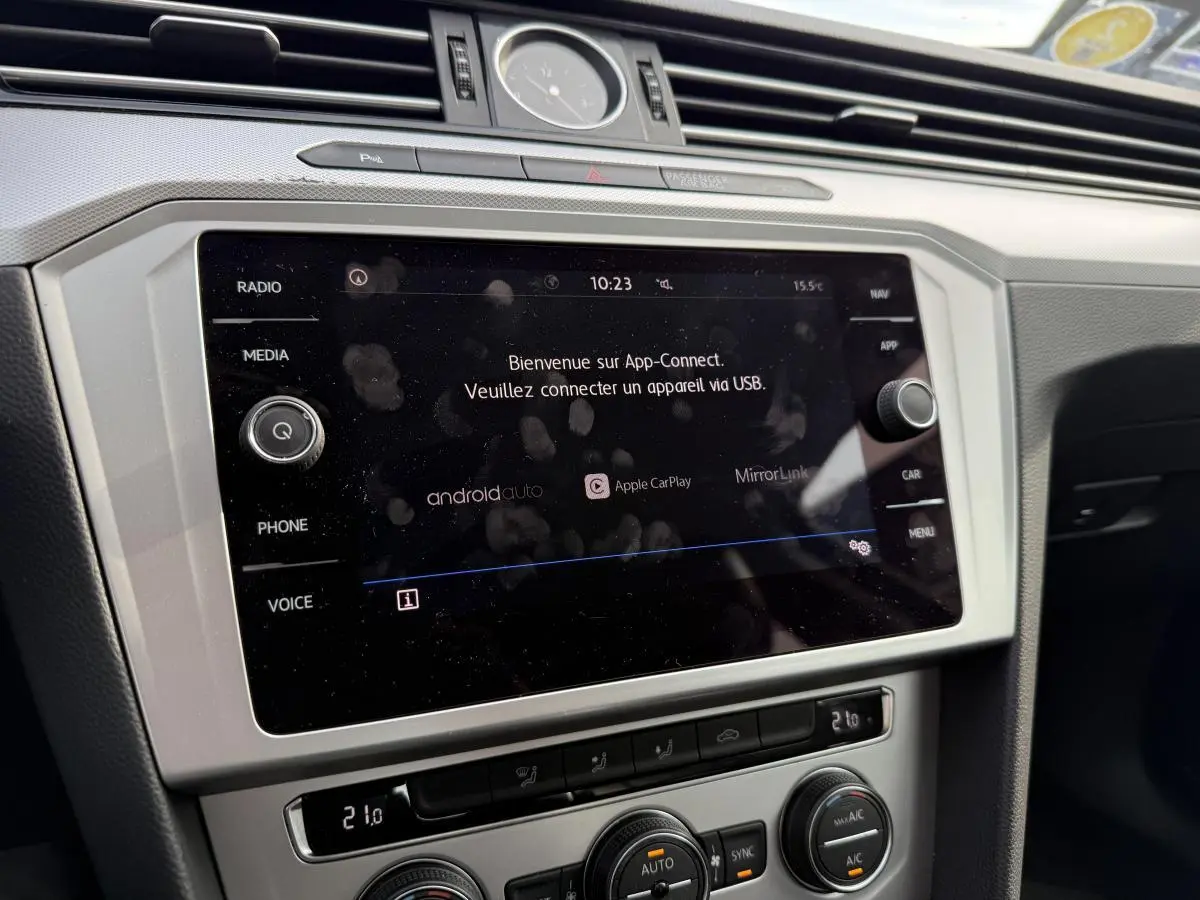 Vue rapprochée de la console centrale argentée de la Volkswagen Passat noire 2018 avec écran tactile et horloge analogique.