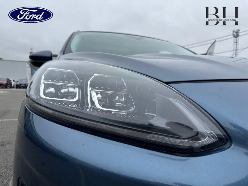 Gros plan sur le phare avant gauche du Ford Kuga 2022 bleu azur métallisé avec détails LED et carrosserie brillante.