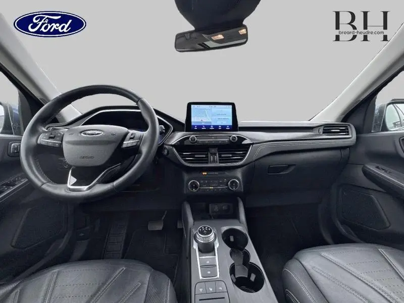 Vue intérieure avant du Ford Kuga 2022 bleu azur, avec tableau de bord moderne et écran tactile central.