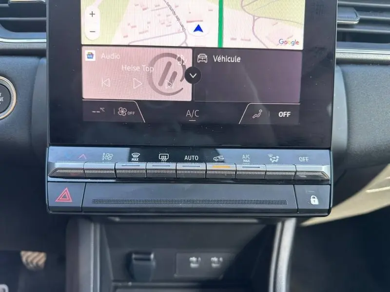 Gros plan sur la console centrale du Renault Captur 2025, boutons climatisation et écran tactile avec navigation visible.