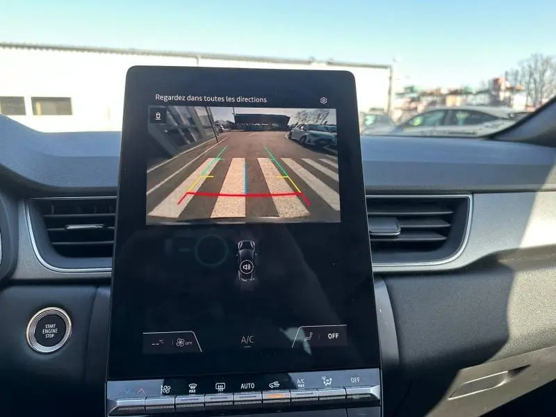 Vue intérieure du tableau de bord du Renault Captur 2025, écran central affichant la caméra de recul avec lignes de guidage colorées.