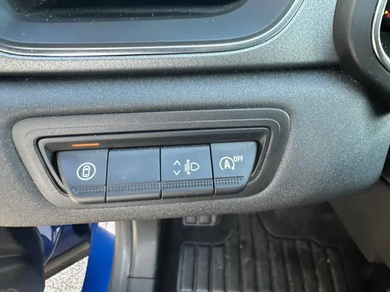 Gros plan sur les commandes du tableau de bord du Renault Captur 2025, finition Bleu Iron/Noir Étoilé, boutons de réglage lumière et arrêt auto.