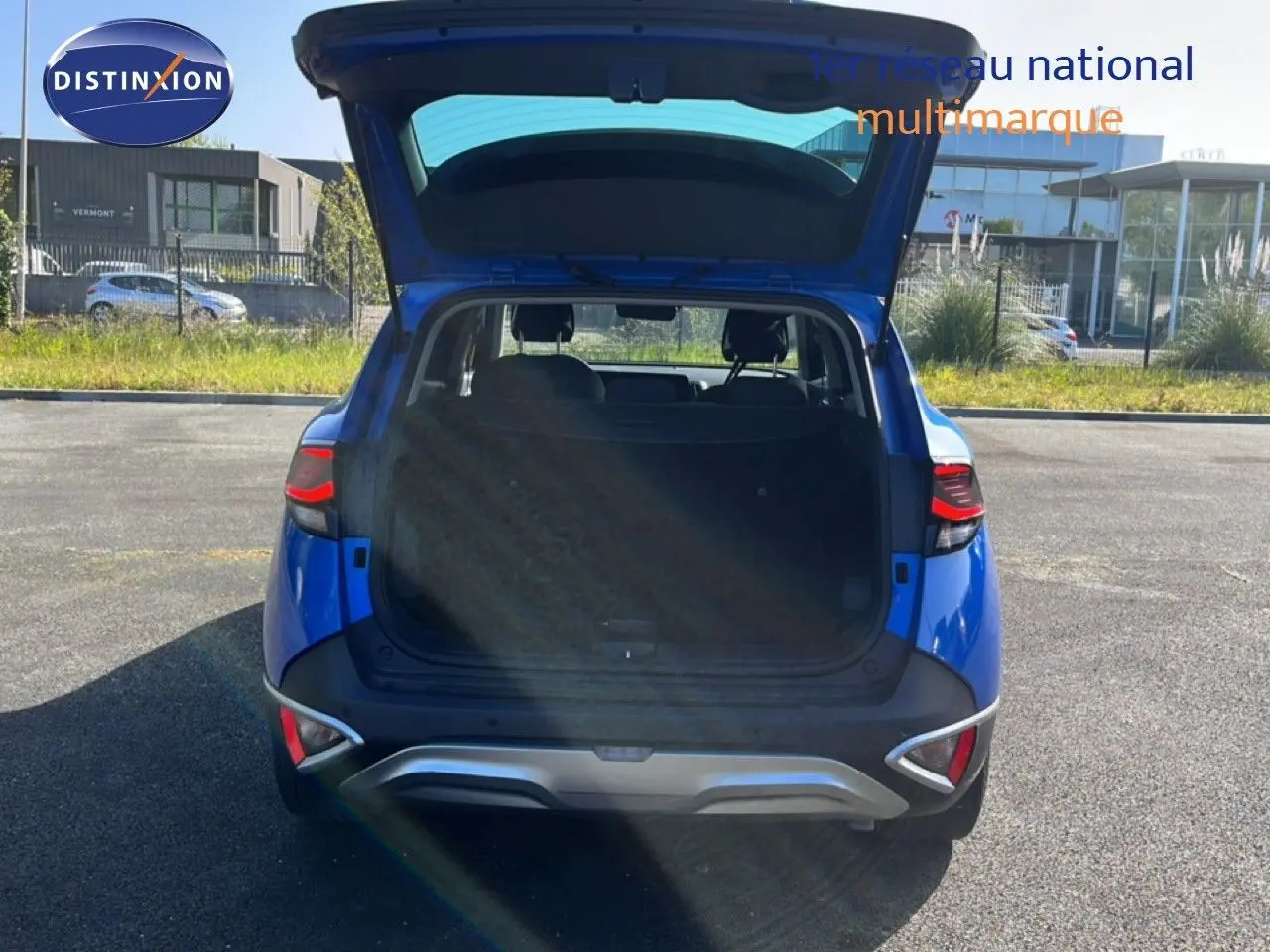Vue arrière d'un Kia Sportage bleu fusion métal 2022 avec coffre ouvert, mettant en valeur son espace de chargement.