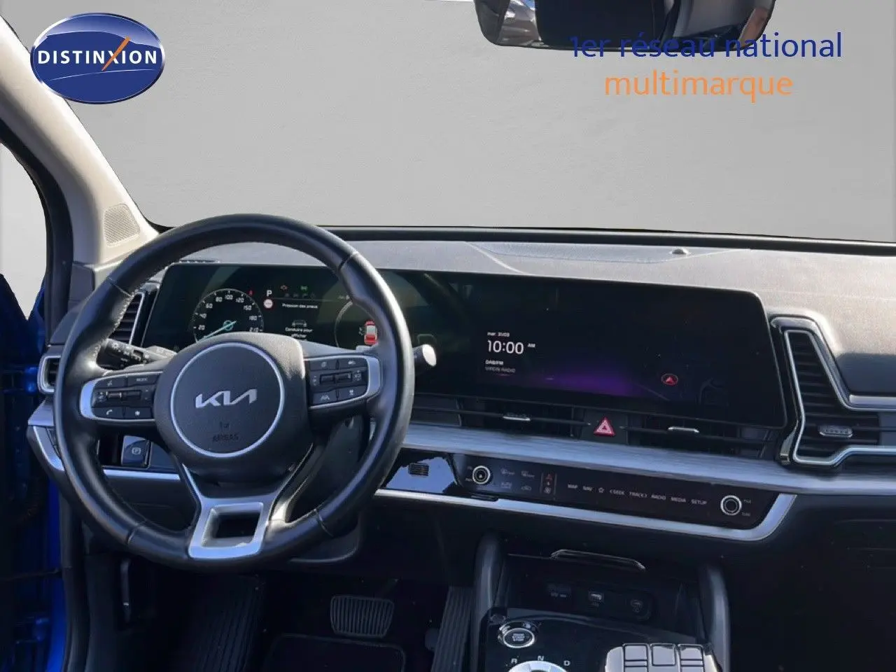 Vue intérieure du tableau de bord et volant noir du Kia Sportage 2022, avec écran tactile large et commandes intégrées.