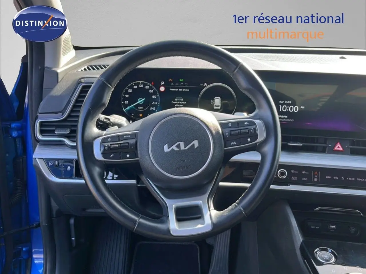 Intérieur du Kia Sportage 2022 bleu fusion, vue centrée sur le volant cuir multifonction et tableau de bord numérique.
