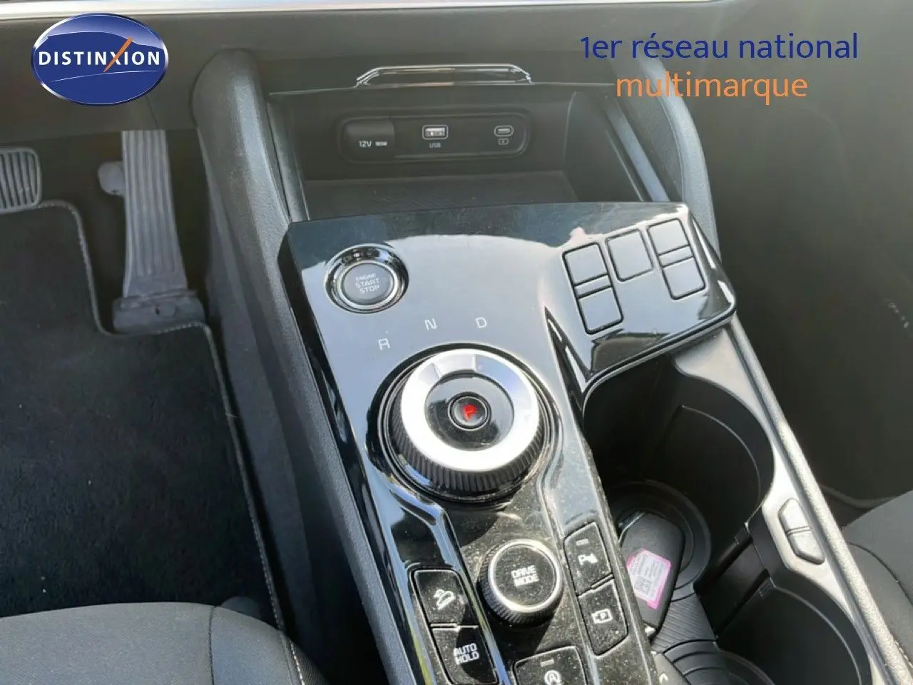 Gros plan sur la console centrale noire brillante du Kia Sportage 2022, montrant la molette de boîte auto et les boutons de contrôle.