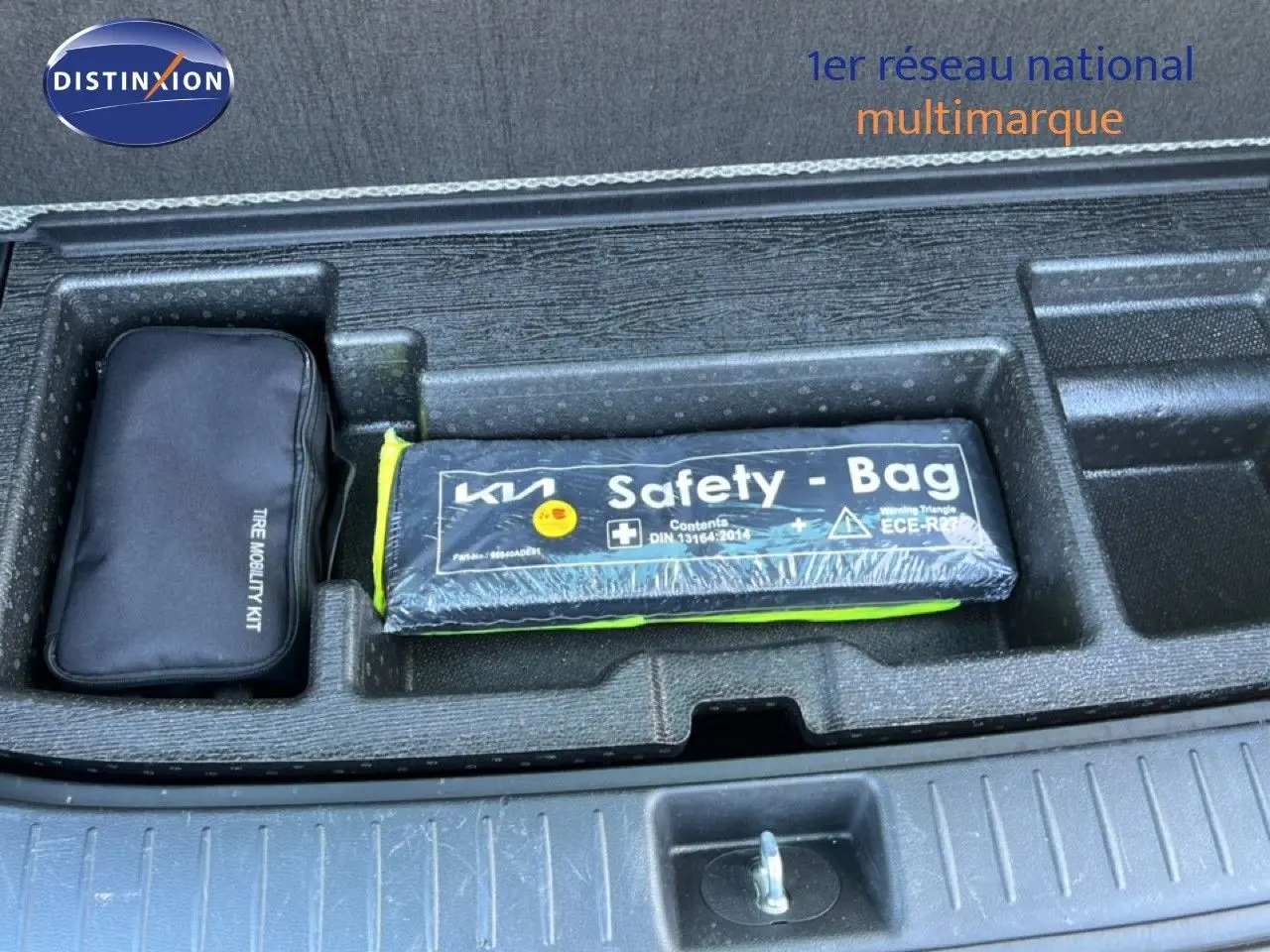 Gros plan sur le coffre du Kia Sportage bleu fusion, montrant le kit mobilité et la trousse de sécurité Safety Bag.