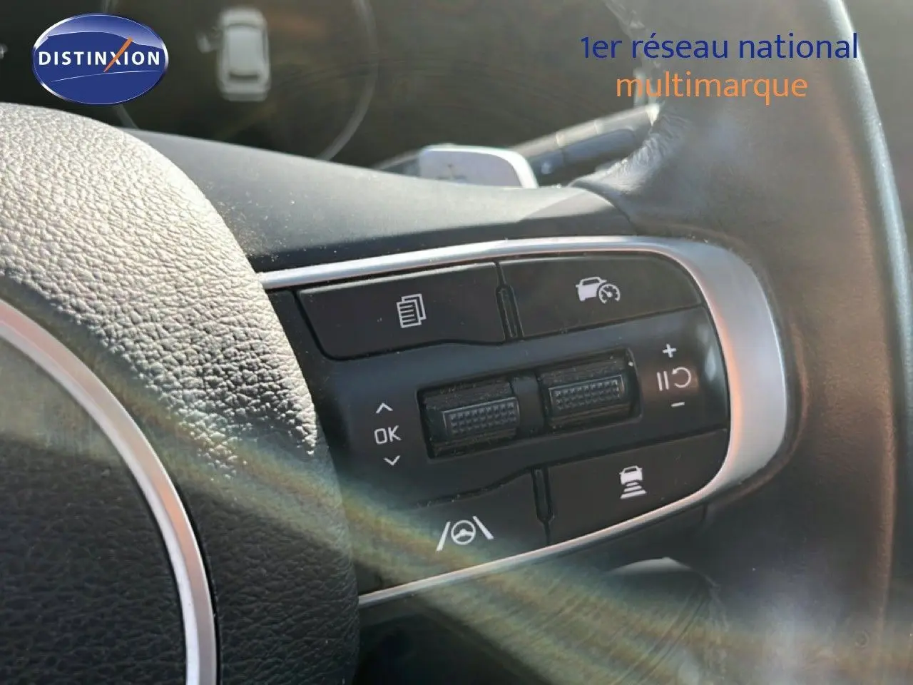 Gros plan sur les commandes au volant en cuir noir du KIA Sportage 2022, boutons de régulateur de vitesse visibles.