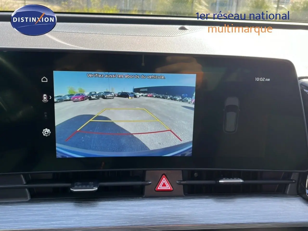 Écran de caméra de recul affichant l'arrière du Kia Sportage bleu fusion métal, vue intérieure du tableau de bord.