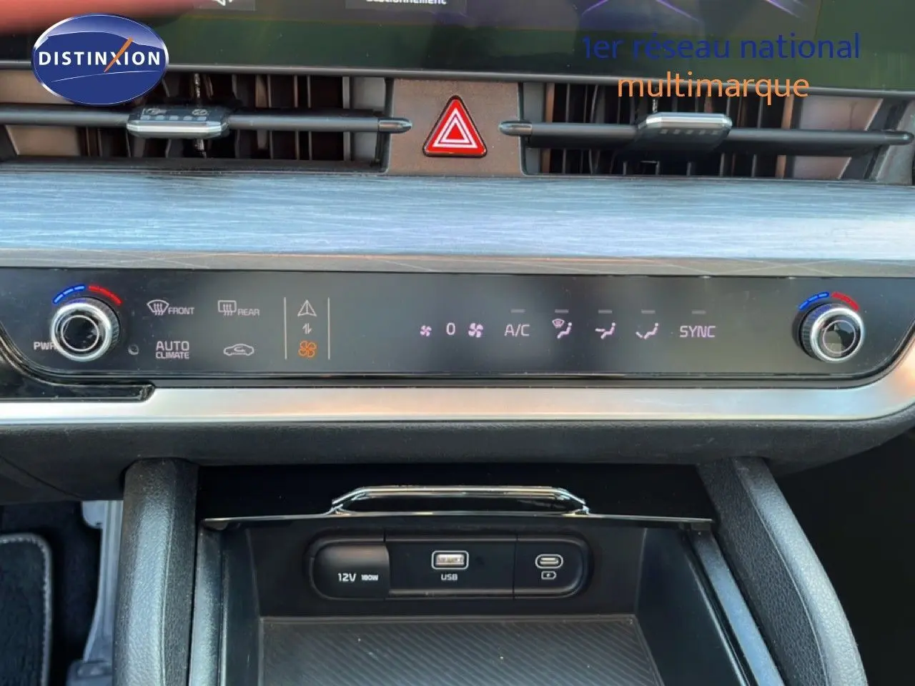 Vue rapprochée du tableau de bord du Kia Sportage bleu fusion métal 2022, mettant en valeur les commandes de climatisation et ports USB.