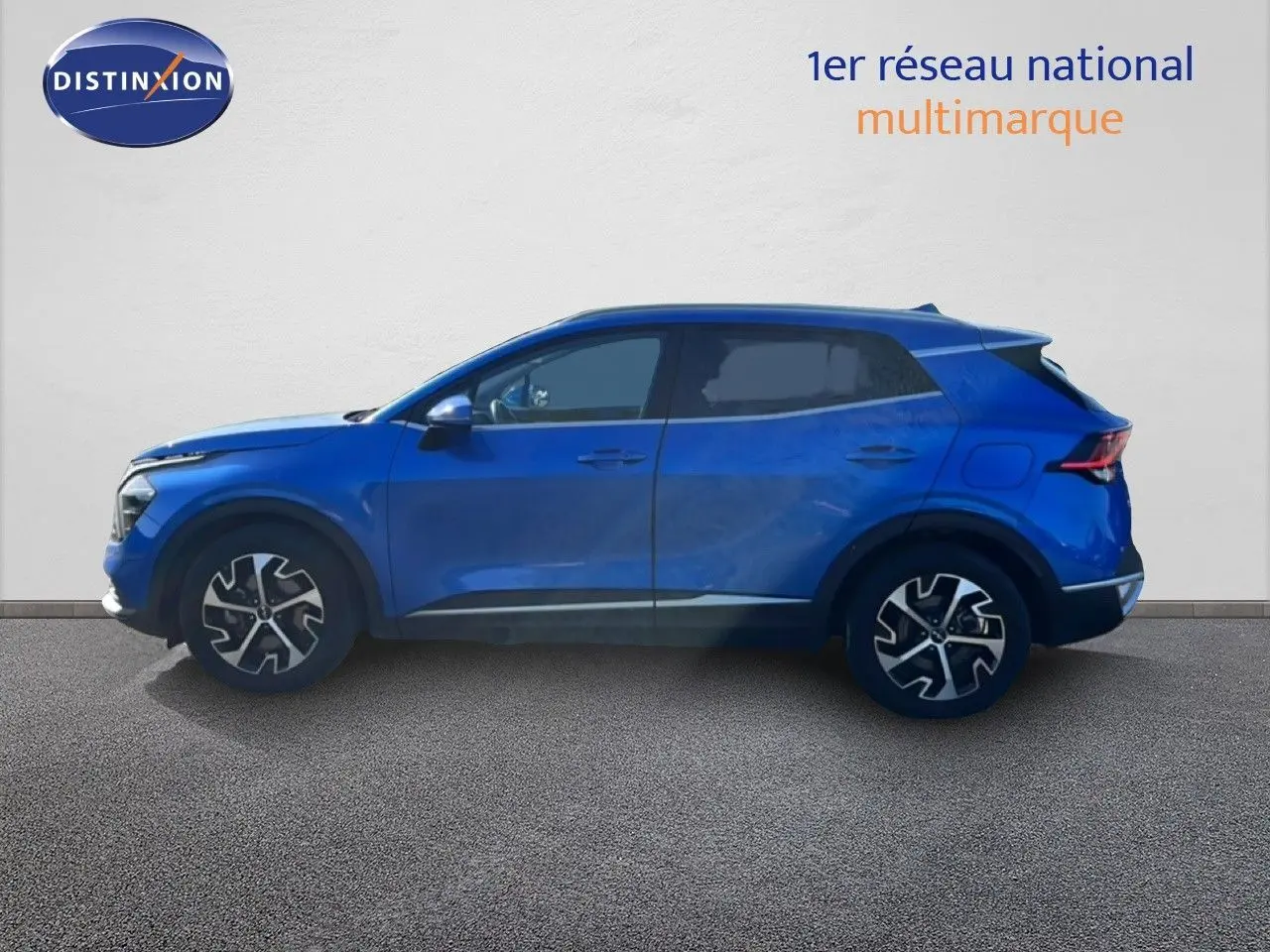 Vue de profil côté gauche d'un Kia Sportage bleu fusion métal 2022 avec jantes alliage bicolores et vitres teintées.