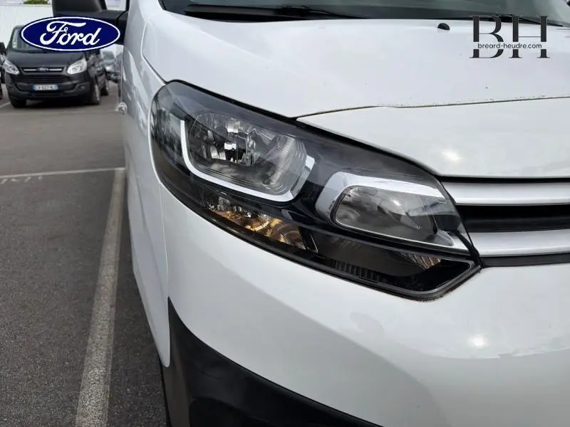 Gros plan sur le phare avant droit du Citroën Jumpy blanc Banquise, mettant en valeur les détails du bloc optique.