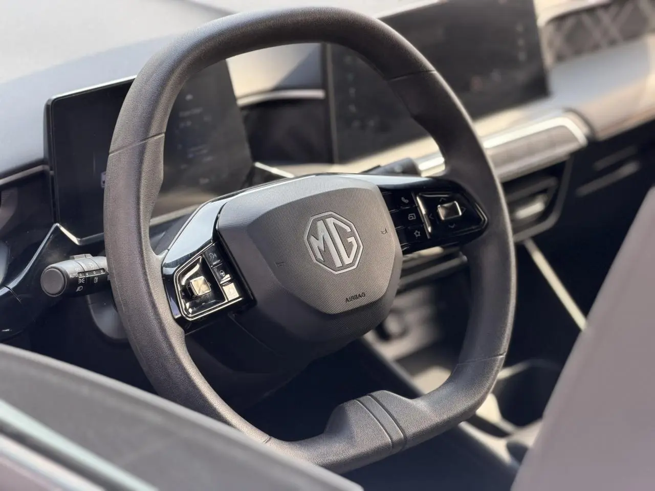 Vue rapprochée du volant noir du MG3 1.5 Hybrid+ 195 Comfort avec tableau de bord numérique en arrière-plan.