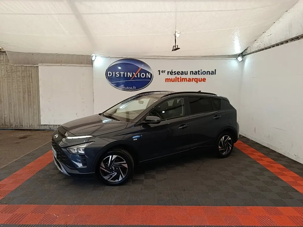 Vue de profil droit d'une Hyundai Bayon gris foncé 2023 dans un showroom avec éclairage intérieur.