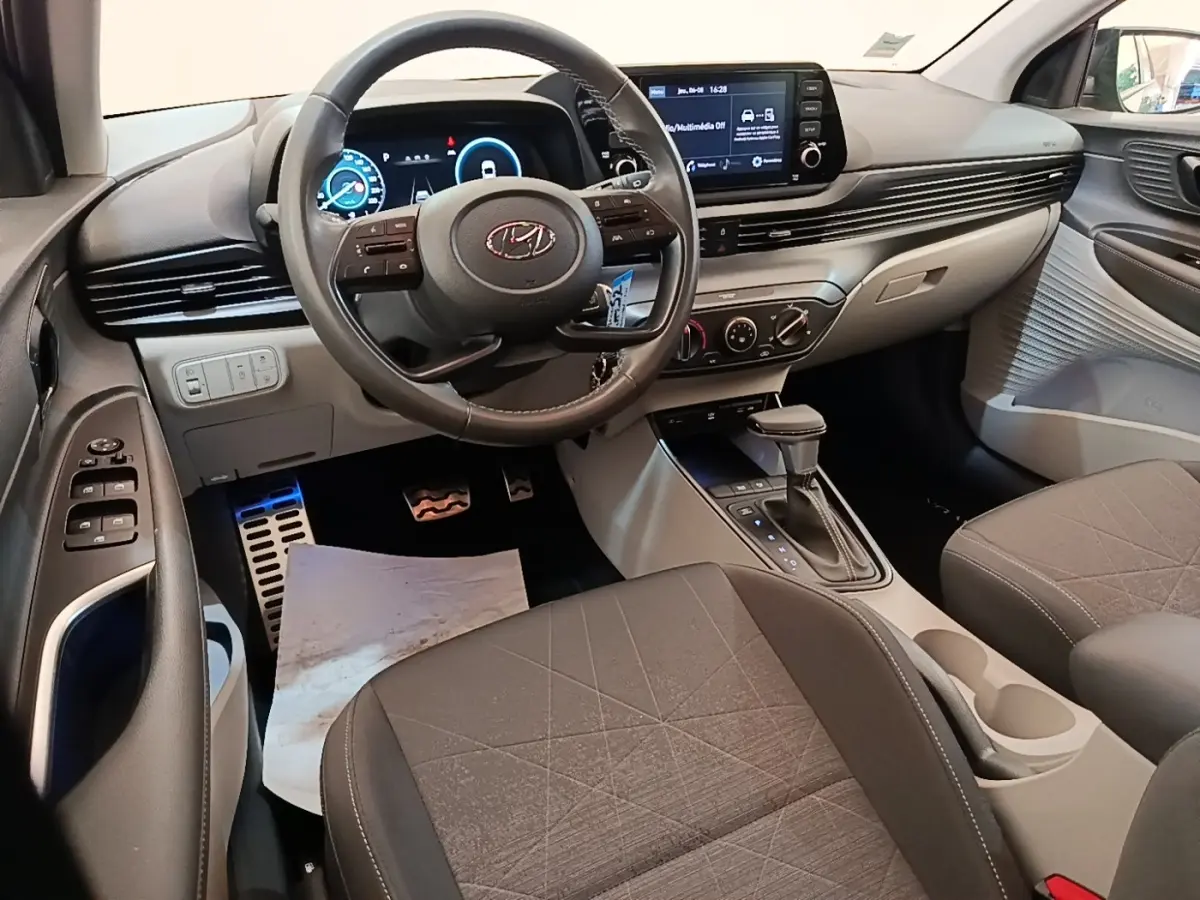 Vue intérieure avant de la Hyundai Bayon 2023, tableau de bord gris avec écran tactile et volant cuir multifonctions.