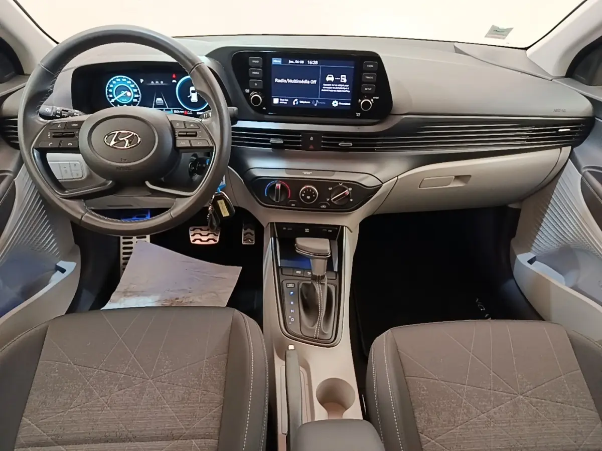 Vue intérieure avant de la Hyundai Bayon 2023, tableau de bord noir avec écran tactile central et volant cuir multifonctions.