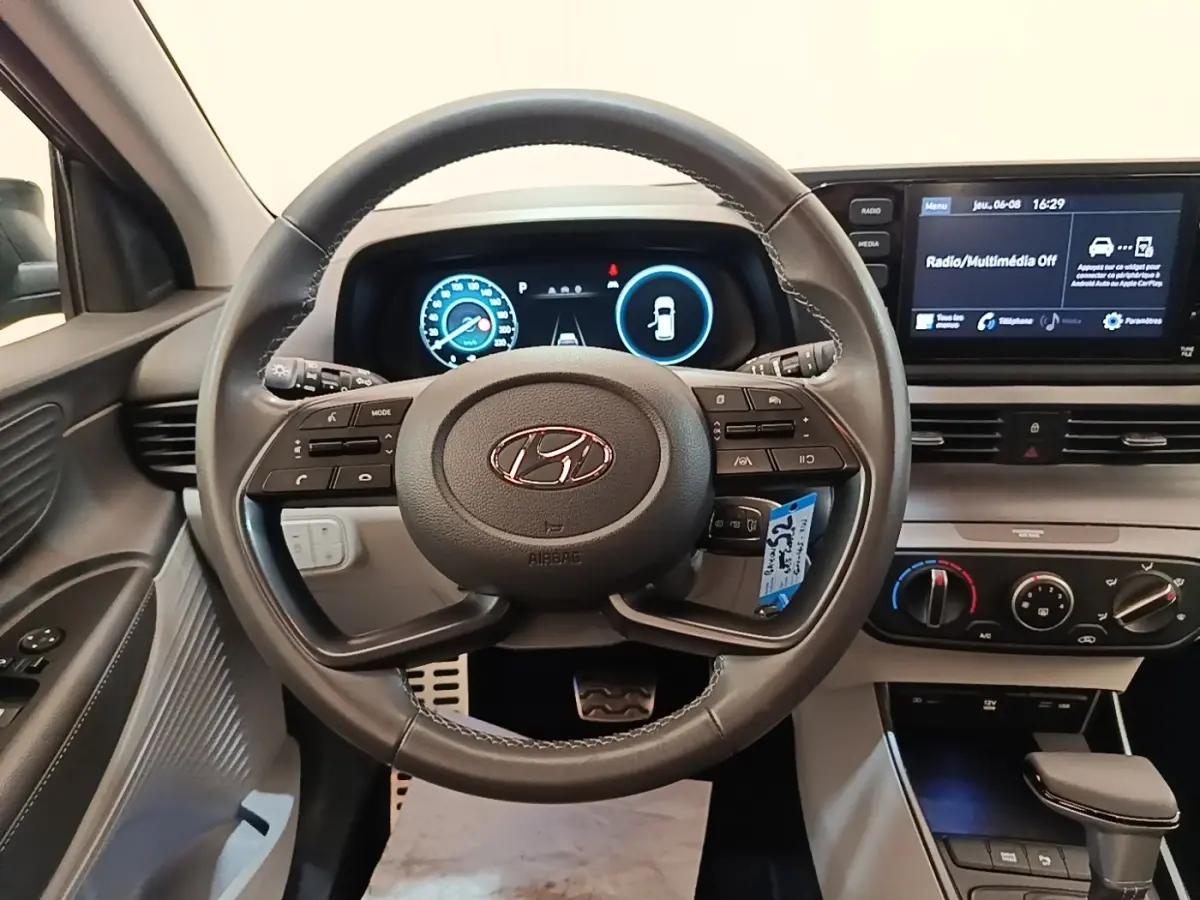 Vue intérieure centrée sur le volant cuir et le tableau de bord numérique du Hyundai Bayon 2023, ambiance moderne et fonctionnelle.