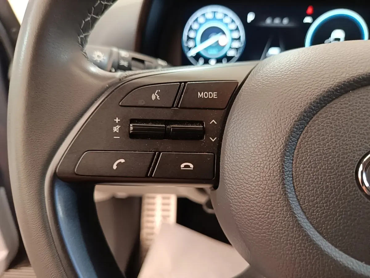 Gros plan sur le volant cuir gris foncé de la Hyundai Bayon 2023 avec commandes multimédia et tableau de bord numérique en arrière-plan.
