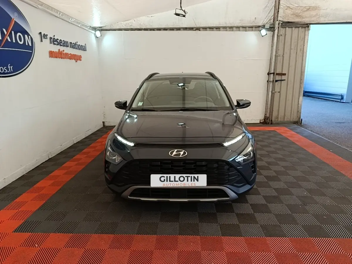 Vue avant d'un Hyundai Bayon gris foncé stationné en intérieur avec calandre noire et phares LED allumés.