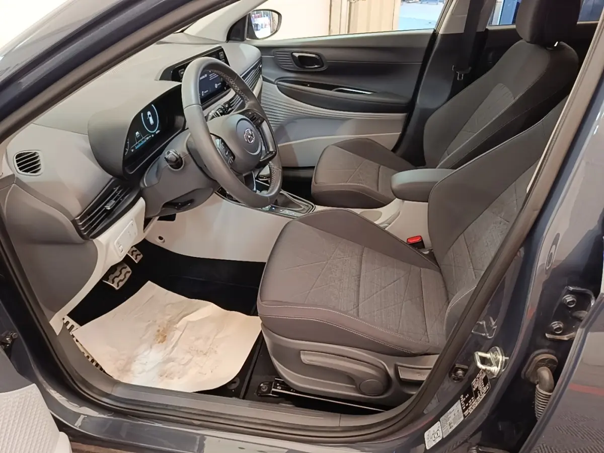 Intérieur avant droit de la Hyundai Bayon gris foncé, avec sièges tissu gris et tableau de bord moderne.