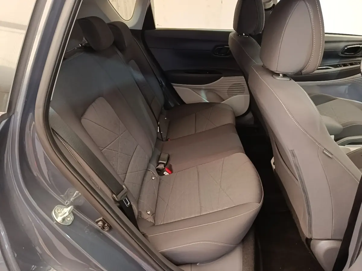 Vue intérieure côté gauche sur les sièges arrière gris foncé du Hyundai Bayon 2023 avec porte ouverte.