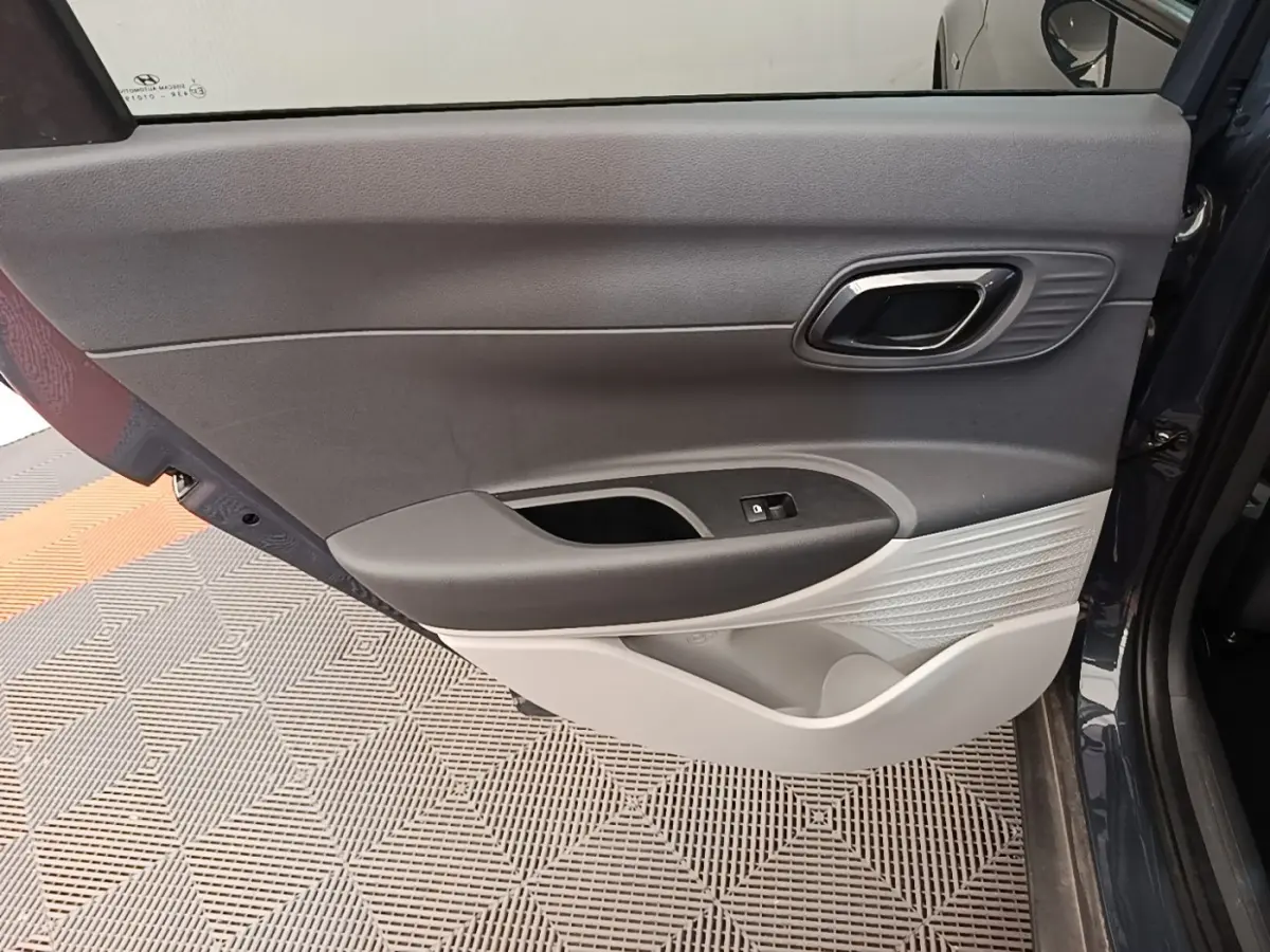 Vue intérieure de la porte arrière droite grise foncée de la Hyundai Bayon 2023 avec poignée et commande de fenêtre.