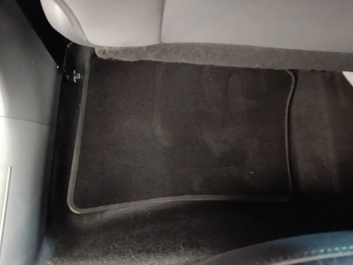 Détail du sol noir avec tapis de sol sous le siège arrière du Hyundai Bayon gris foncé 2023.