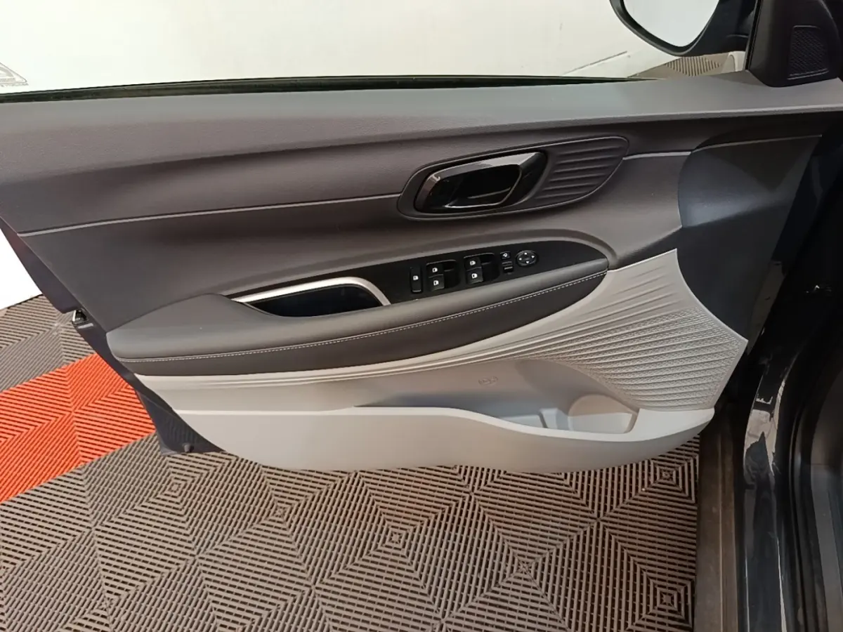 Vue intérieure côté gauche de la porte avant gris foncé de la Hyundai Bayon avec commandes de vitres et poignée intégrée.