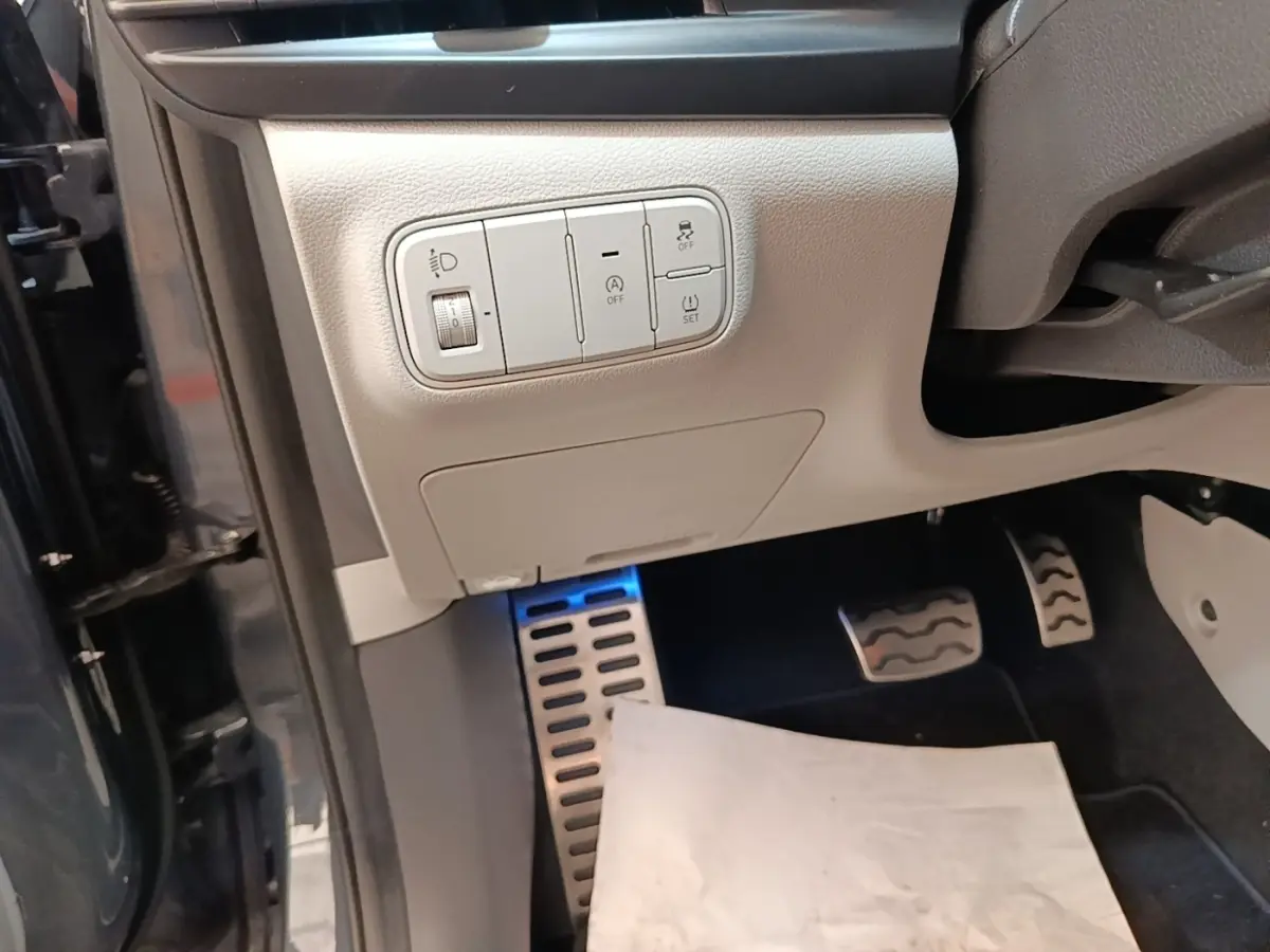 Détail intérieur côté conducteur du Hyundai Bayon gris foncé 2023, montrant les commandes d’éclairage et les pédales sport.