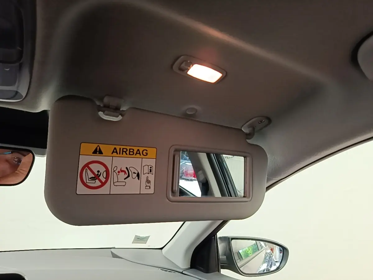 Vue intérieure côté conducteur du pare-soleil avec miroir et avertissement airbag dans un Hyundai Bayon gris foncé 2023.