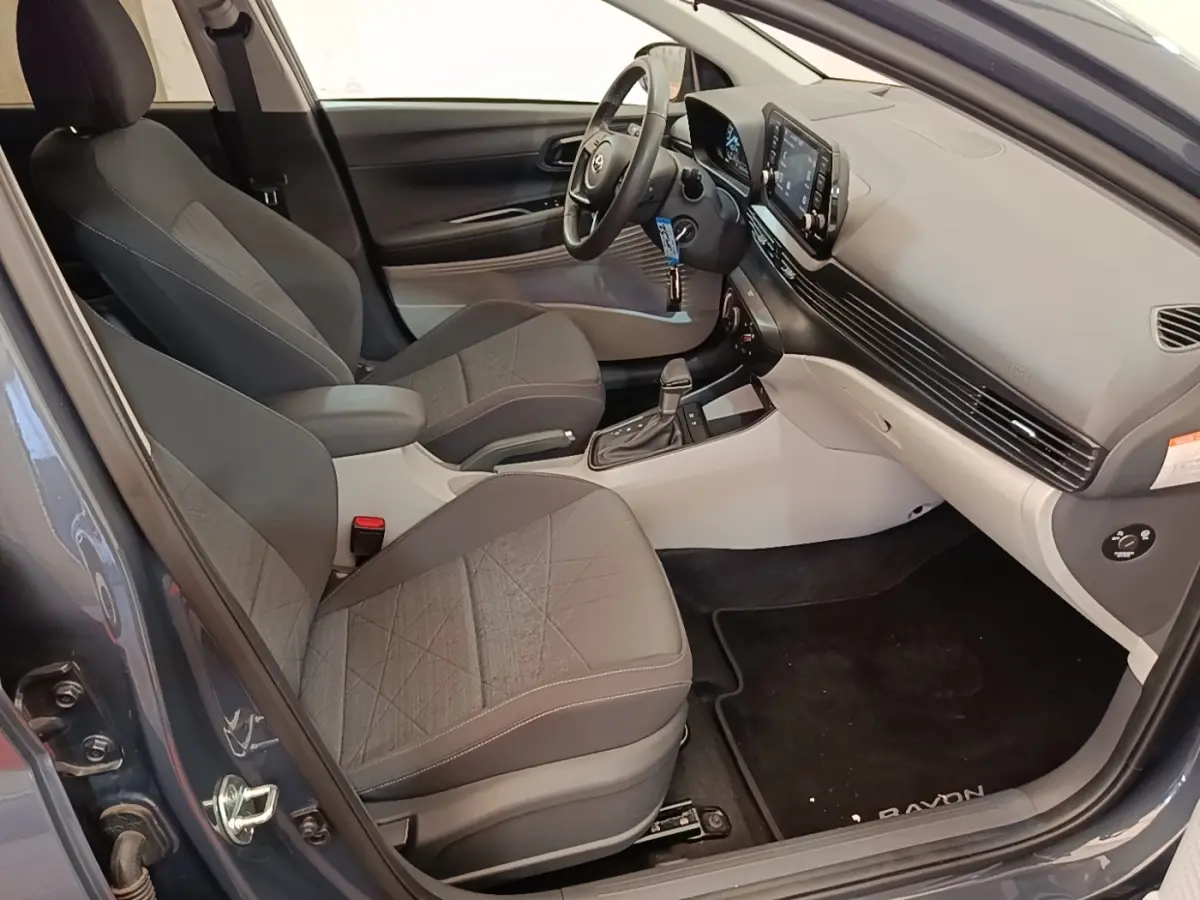 Vue intérieure côté conducteur de la Hyundai Bayon gris foncé 2023, avec sièges tissu et tableau de bord moderne.